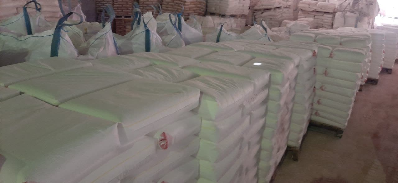 Image of Warehouse with stacked white bags Calcium Carbonate Paper Making on pallets.